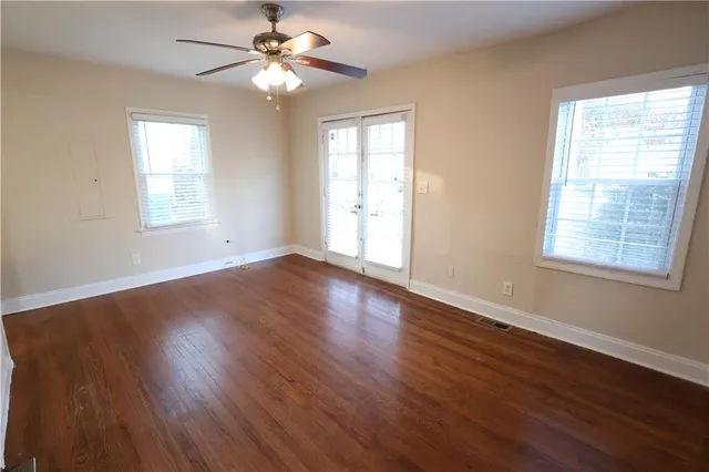 a view of an empty room with wooden floor and a window