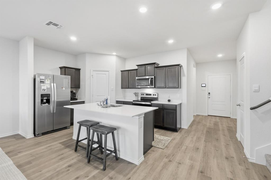 1354 Turkey Run Drive Denton, TX 76207 - Photo 9 of 29 a kitchen with stainless steel appliances a stove top oven a refrigerator a sink and white cabinets with wooden floor