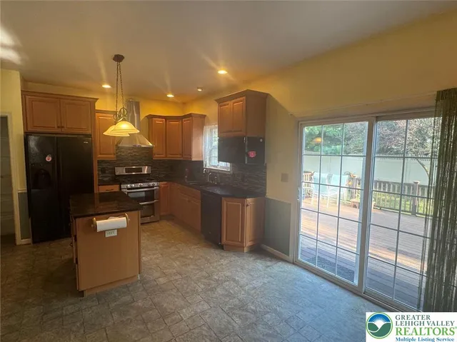 a kitchen with stainless steel appliances kitchen island granite countertop a refrigerator a stove and a sink with large window