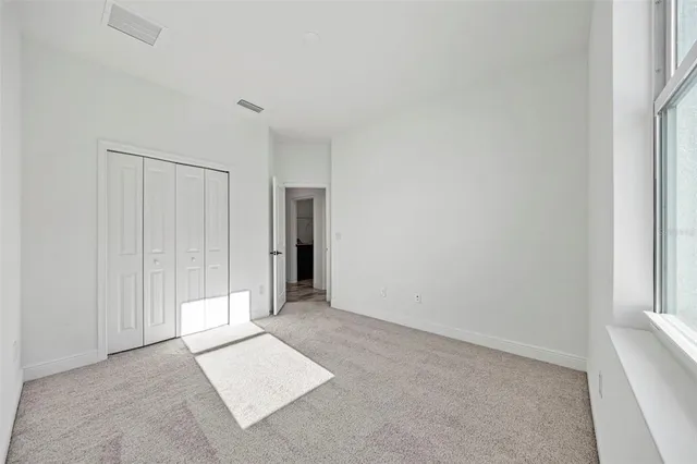 an empty room with chandelier fan and windows