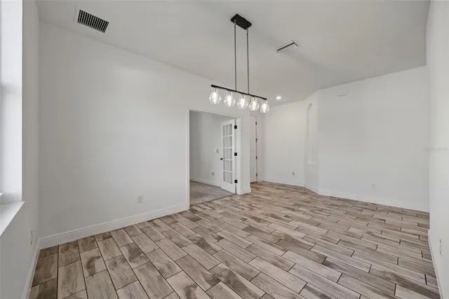 a view of a room with wooden floor a ceiling fan and a window