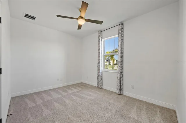 an empty room with ceiling fan and window