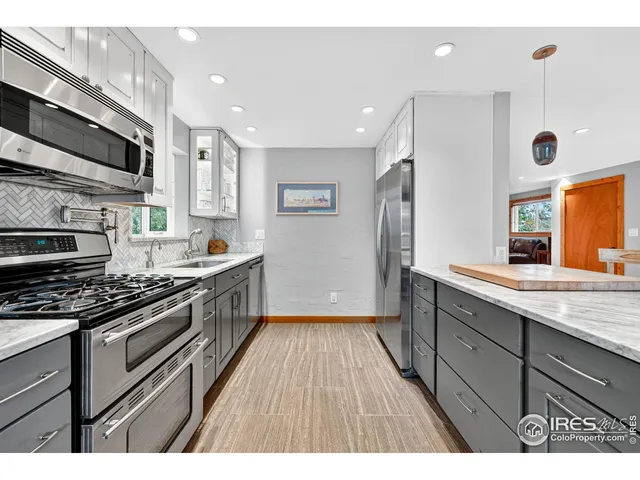 a kitchen with stainless steel appliances kitchen island granite countertop a stove a sink dishwasher and a microwave oven with wooden floor