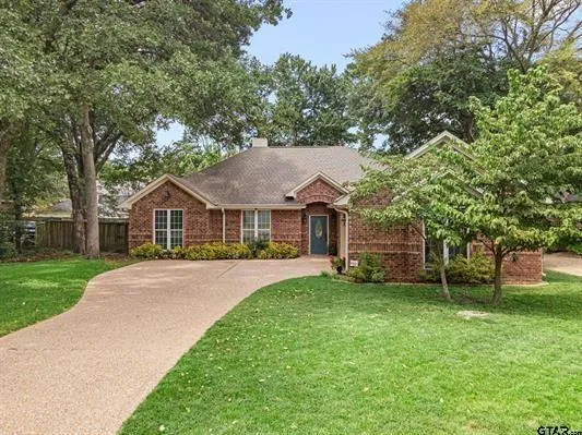 a front view of a house with a garden and trees