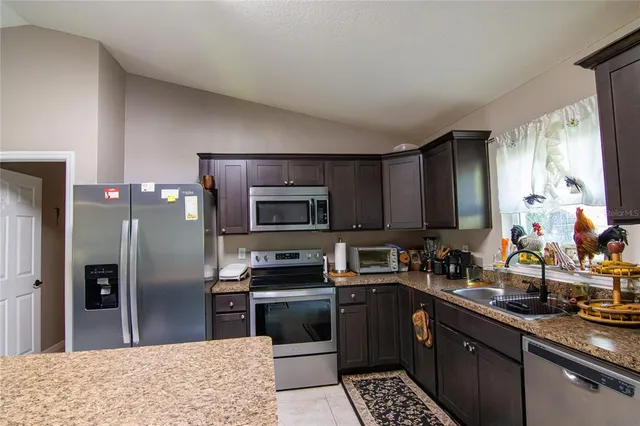 a kitchen with stainless steel appliances kitchen island granite countertop a refrigerator stove and sink