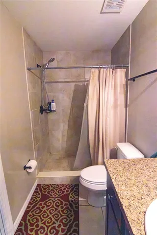 a bathroom with a granite countertop sink toilet and shower