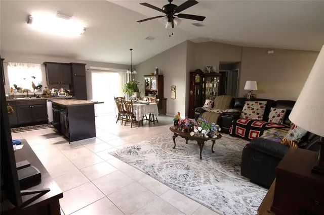 a living room with furniture and a dining table with kitchen appliances