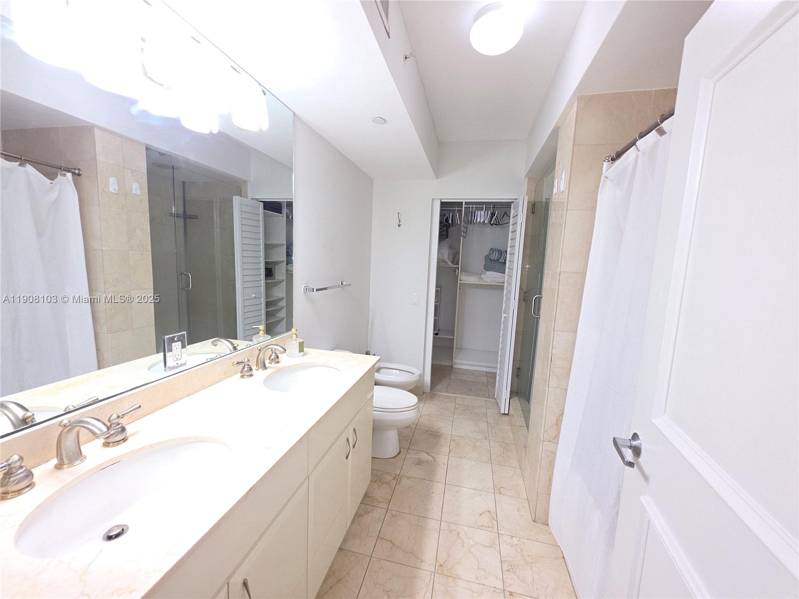 6365 Collins Avenue, Unit 1511 Miami Beach, FL 33141 - Photo 11 of 15 a spacious bathroom with a double vanity sink a mirror and a bathtub