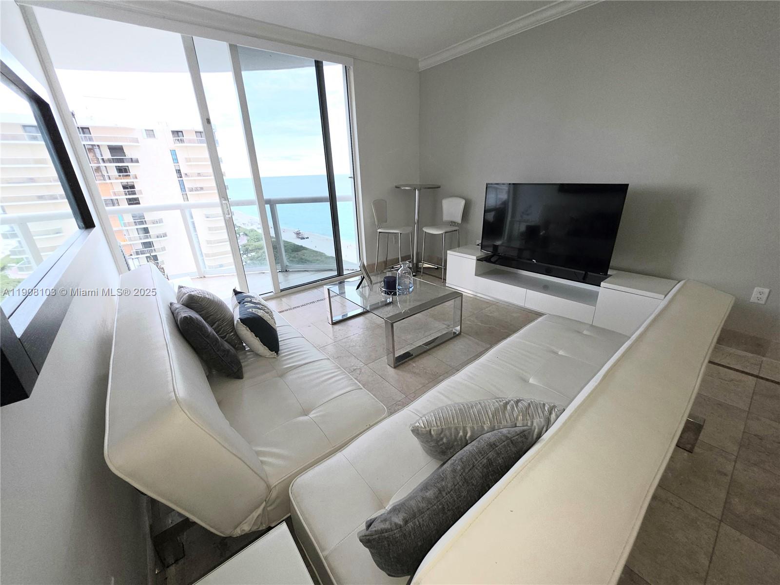 6365 Collins Avenue, Unit 1511 Miami Beach, FL 33141 - Photo 5 of 15 a living room with furniture and a flat screen tv