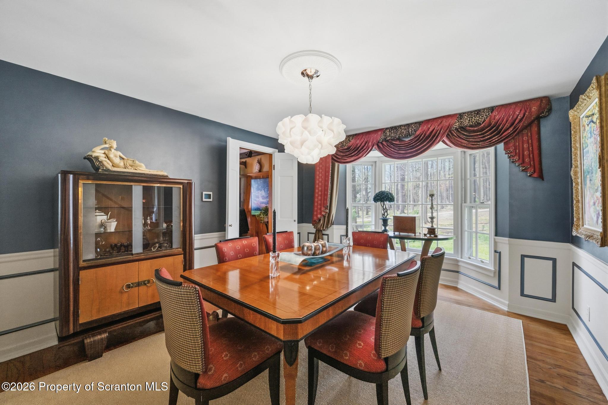 202 Woodlea Road Glenburn, PA 18414 - Photo 13 of 28 a dining room with wooden floor a chandelier a wooden table and chairs