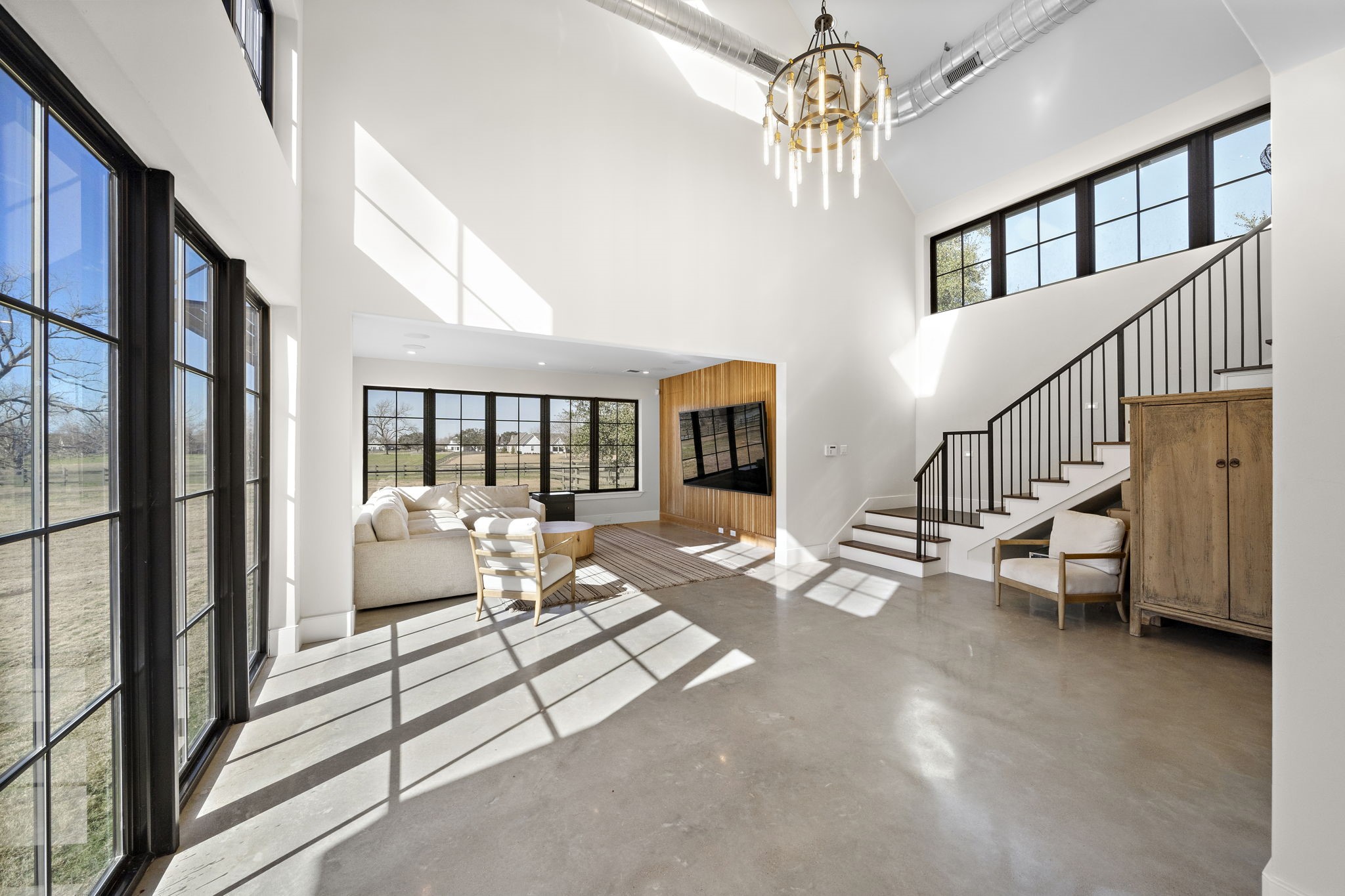 5511 Fulbrook Road Fulshear, TX 77441 - Photo 41 of 50 Views of the property abound with windows throughout the downstairs of the Casita. Gorgeous concrete floors, exposed ductwork, stunning chandelier, and a decorative wood wall highlight this space.