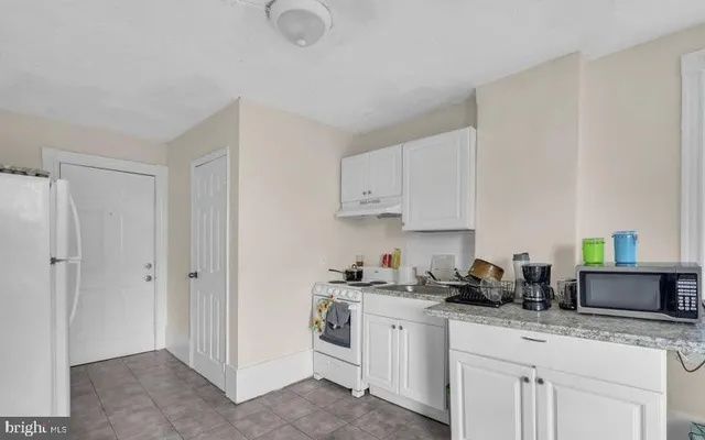 a kitchen with granite countertop white cabinets and white appliances