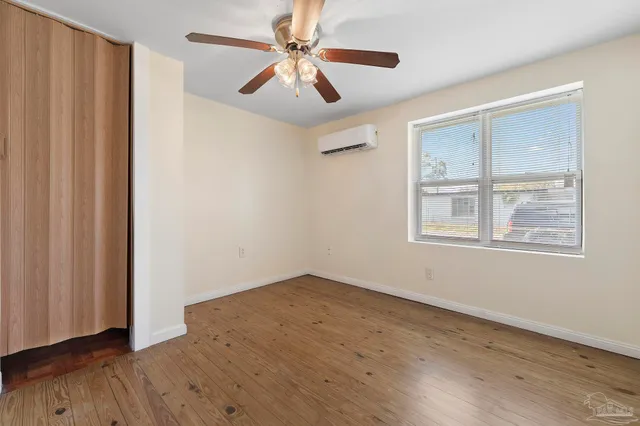 a view of empty room with wooden floor and fan
