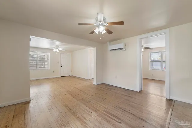a view of an empty room with wooden floor and a ceiling fan
