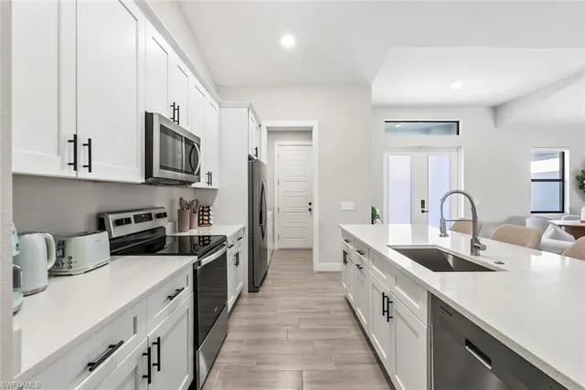 a large white kitchen with stainless steel appliances granite countertop lots of counter space a sink and a refrigerator