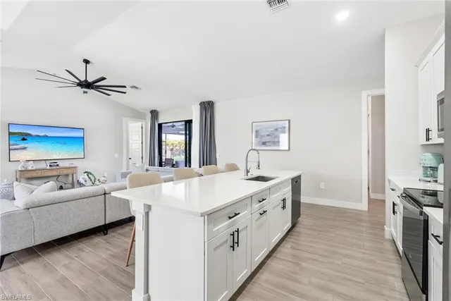 a living room with stainless steel appliances kitchen island hardwood floor and a sink