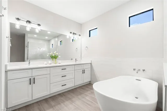 a spacious bathroom with a double vanity sink mirror and bathtub
