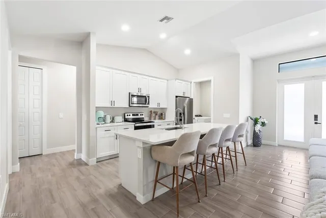 a view of kitchen with stainless steel appliances refrigerator microwave and dining table