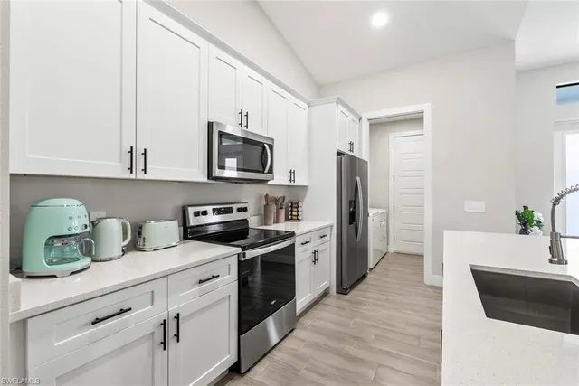 a kitchen with a sink a refrigerator and a stove top oven with wooden floor