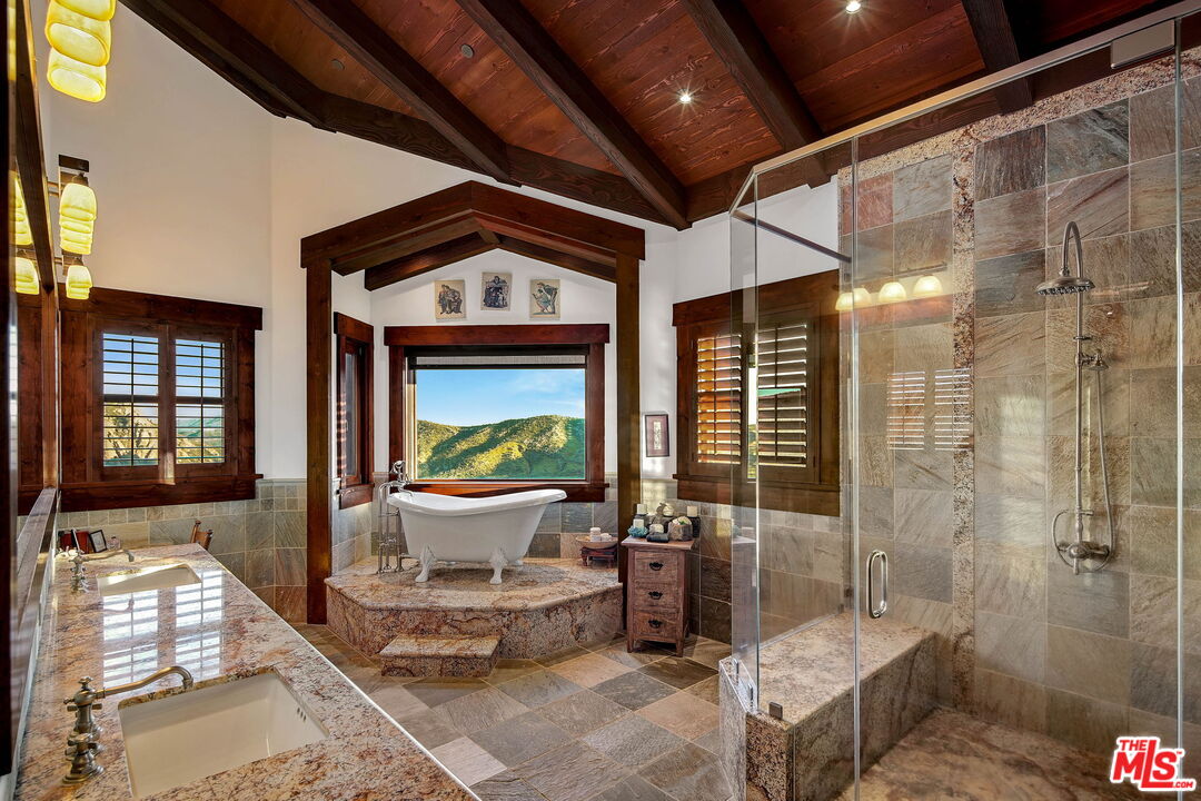 12486 Yerba Buena Road Malibu, CA 90265 - Photo 22 of 68 a spacious bathroom with a granite countertop sink a toilet a mirror and shower
