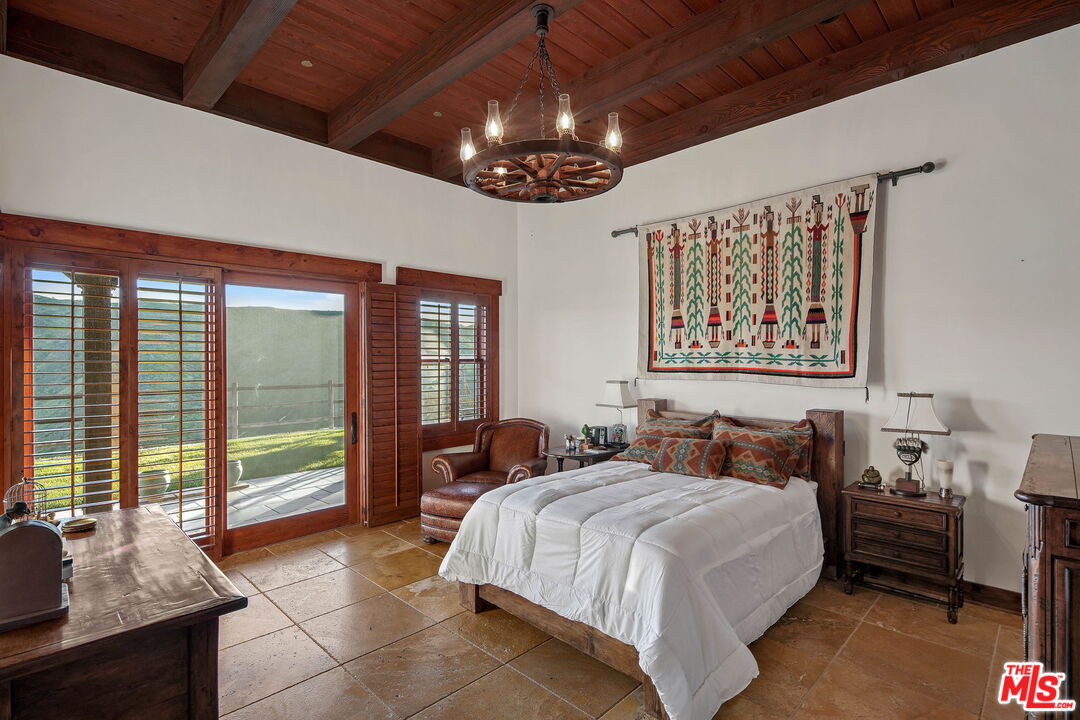 12486 Yerba Buena Road Malibu, CA 90265 - Photo 27 of 68 a spacious bedroom with a large bed and a chandelier