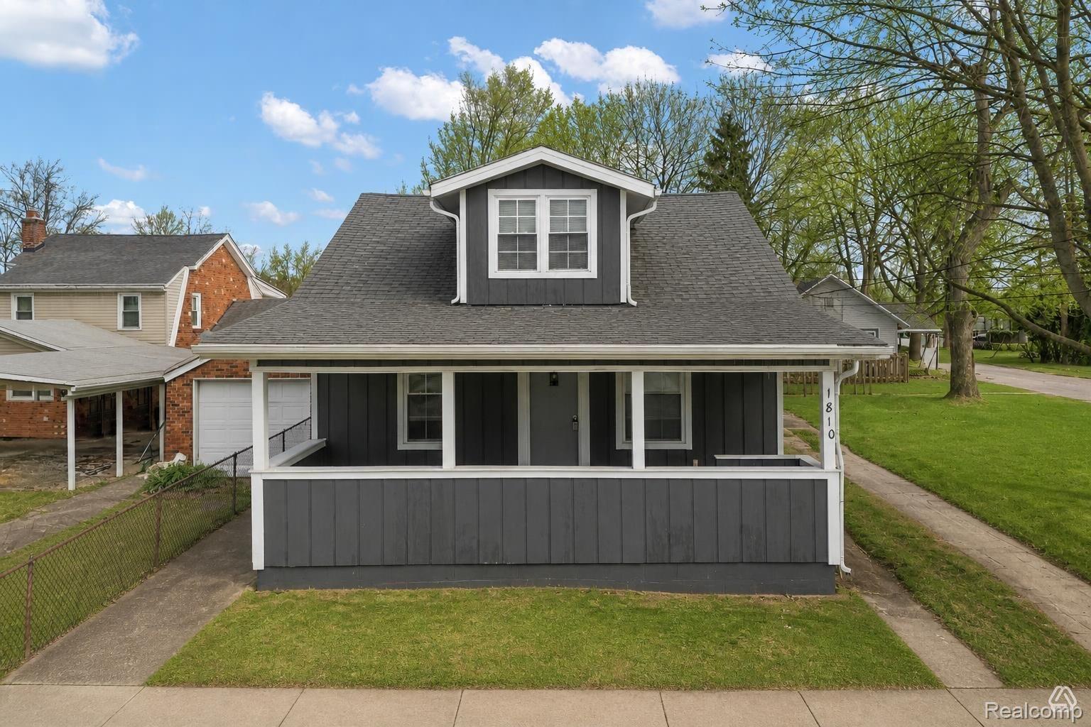 1810 Manse Road Waterford, MI 48328 - Photo 1 of 34 Dormer-style home featuring a covered front porch, dark siding, white trim, and a gabled roof