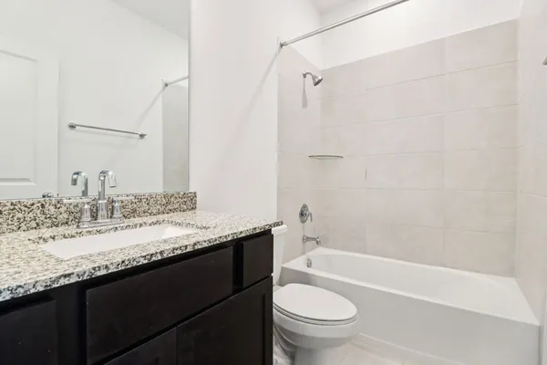 a bathroom with a granite countertop sink a toilet and bathtub