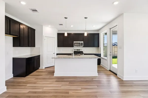 a large kitchen with stainless steel appliances kitchen island granite countertop a stove top oven a sink and a granite counter top