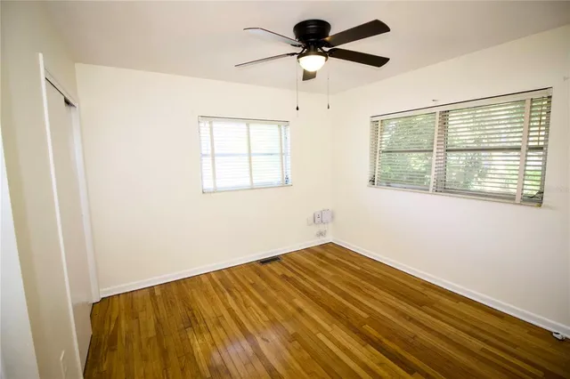 a view of empty room with wooden floor and fan