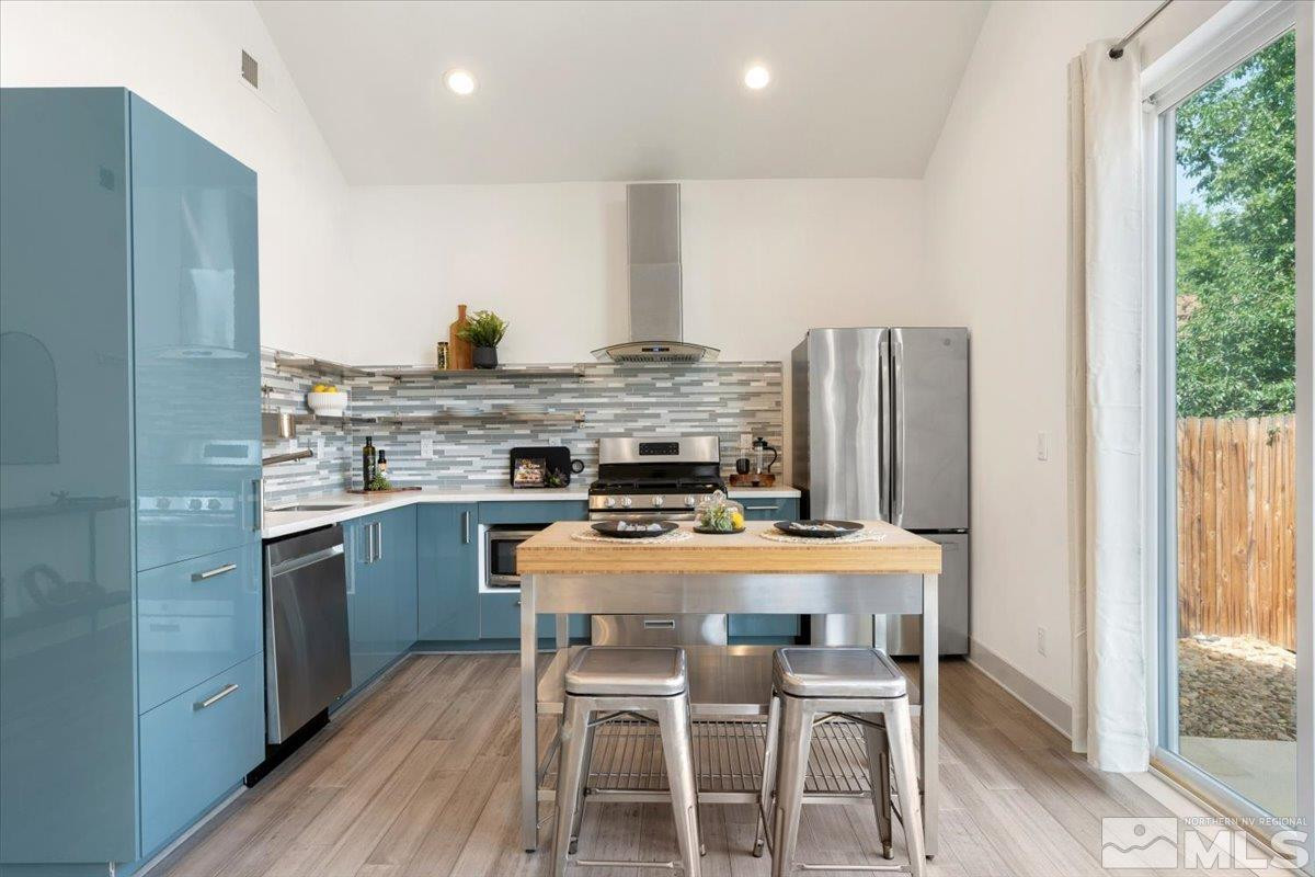 1219 Lander Street Reno, NV 89509 - Photo 9 of 18 a kitchen with stainless steel appliances a dining table chairs and wooden floor