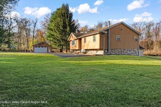 a front view of house with yard and trees in the background