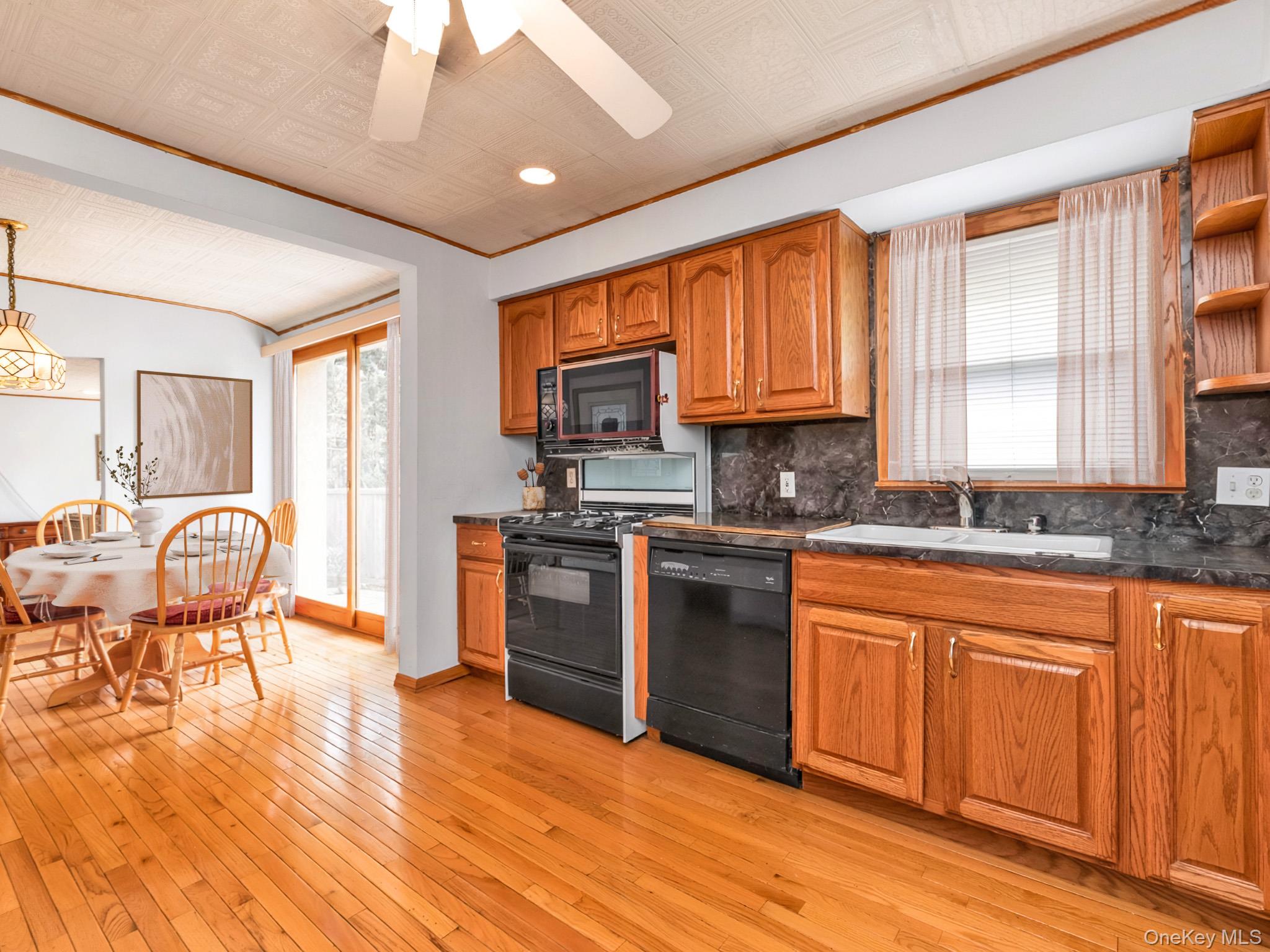 104 Vesper Court Babylon, NY 11702 - Photo 4 of 16 a kitchen with granite countertop a stove top oven a sink dishwasher a dining table and chairs with wooden floor
