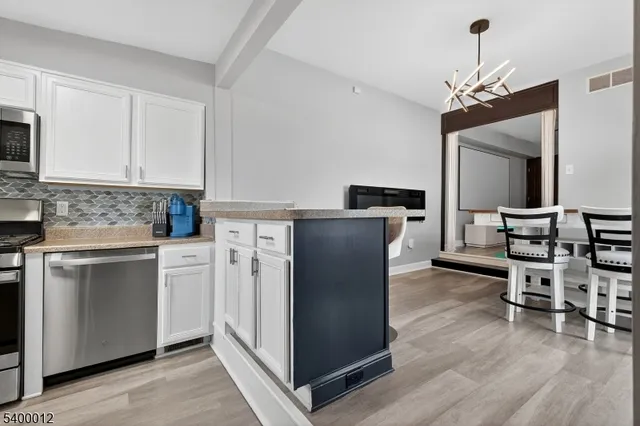 a kitchen with granite countertop white cabinets stainless steel appliances and a sink