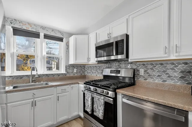 a kitchen with white cabinets and sink