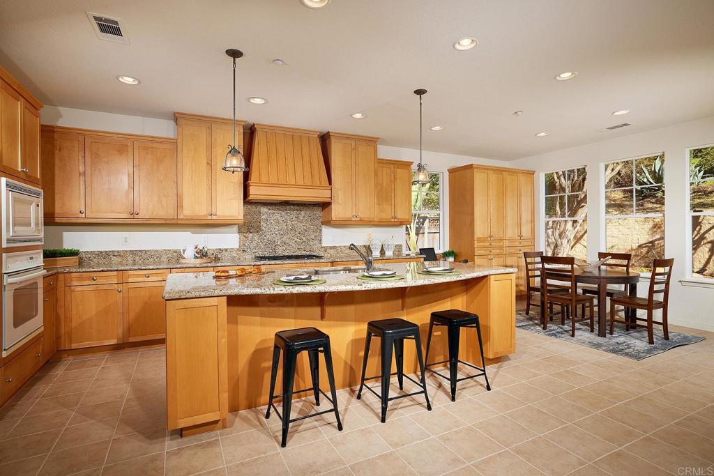 293 Star Jasmine Lane Encinitas, CA 92024 - Photo 17 of 37 a large kitchen with kitchen island granite countertop a stove a sink a dining table and chairs