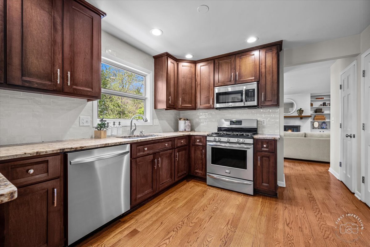 1508 Dunstan Road Geneva, IL 60134 - Photo 12 of 30 a kitchen with stainless steel appliances granite countertop wooden cabinets a stove a sink and dishwasher with wooden floor