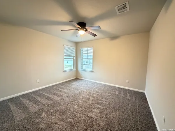 an empty room with windows and fan