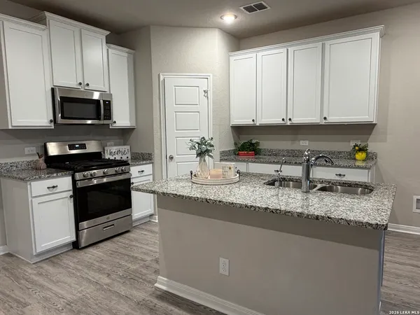 a kitchen with granite countertop a sink a stove and cabinets