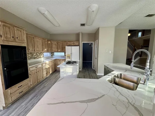 a kitchen with stainless steel appliances kitchen island granite countertop a refrigerator a stove a sink dishwasher and white cabinets with wooden floor