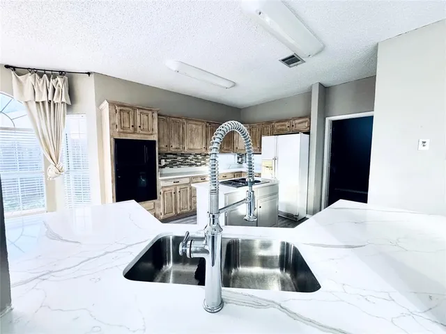 a kitchen with stainless steel appliances kitchen island granite countertop a refrigerator a stove top oven and white cabinets