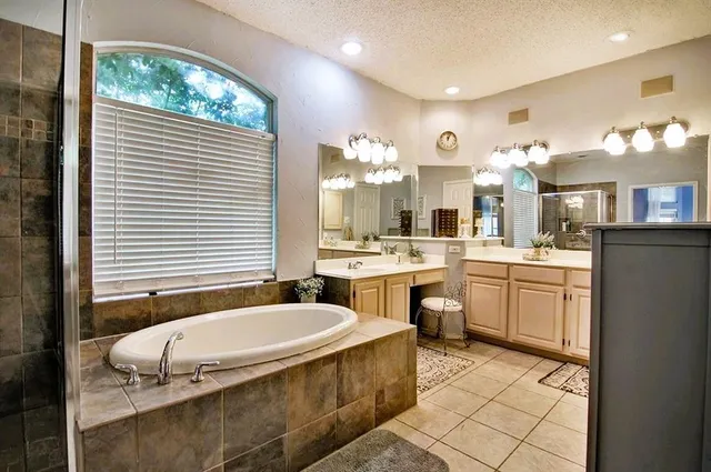a spacious bathroom with a tub sink and mirror