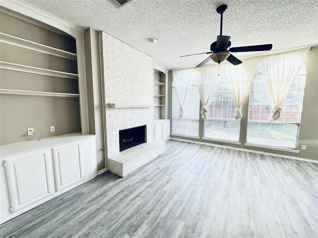 a view of a livingroom with wooden floor a ceiling fan and windows
