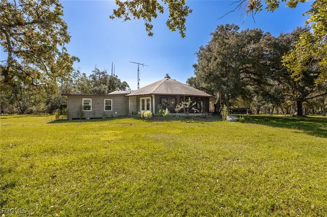 a backyard of a house with a yard and large trees