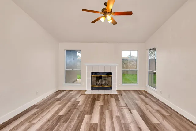 wooden floor fireplace and windows in an empty room