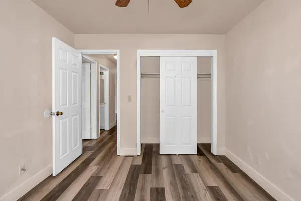 a view of an empty room with window and wooden floor