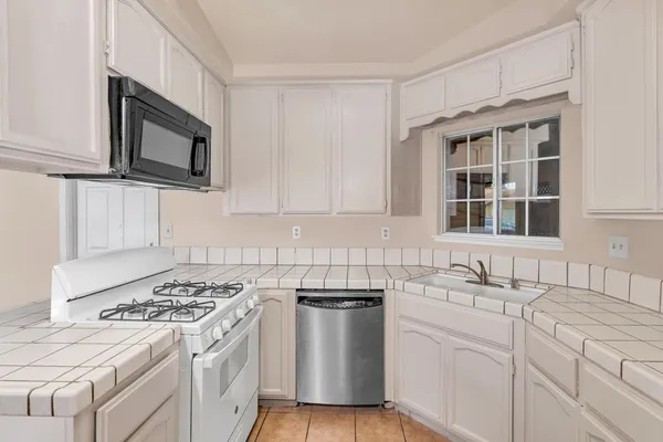 a kitchen with cabinets appliances a sink and a window