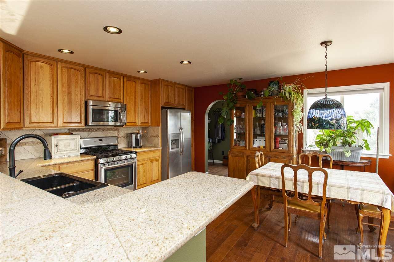 1931 Morgan Road Reno, NV 89521 - Photo 8 of 40 a kitchen with stainless steel appliances granite countertop a stove a sink dishwasher a refrigerator with a dining table and chairs with wooden floor