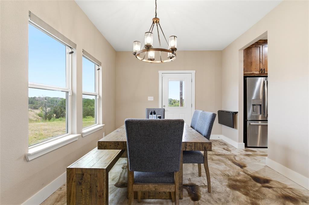 139 Kriston Lane Springtown, TX 76082 - Photo 12 of 39 Dining area featuring wood-finish flooring, a contemporary chandelier, and multiple windows