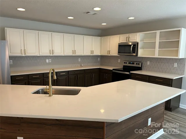 a kitchen with kitchen island a sink dishwasher a stove and white cabinets with wooden floor