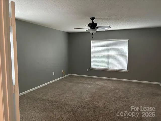 an empty room with a window and a ceiling fan